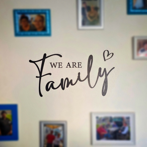 Bilderwand. In der Mitte steht We are familiy.